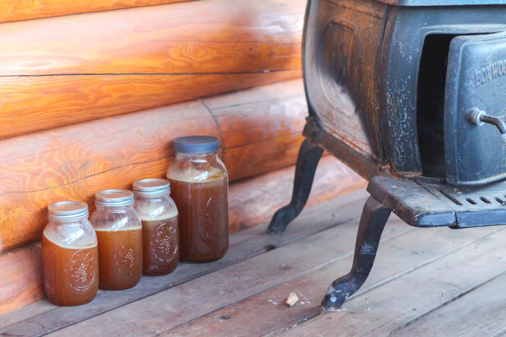 Four jars of frozen stock on a porch.
