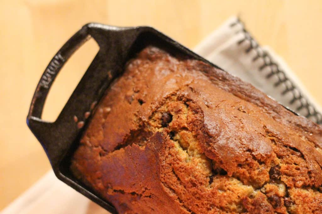Loaf of banana bread in a black pan.