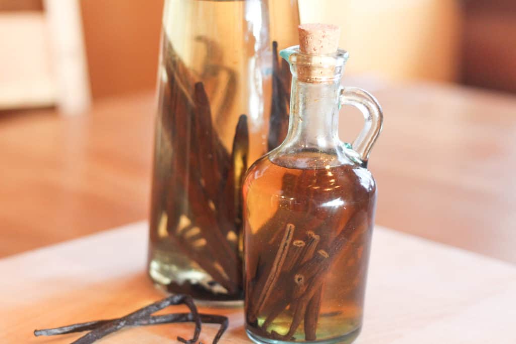 Two glass bottles with vanilla beans for vanilla extract in them