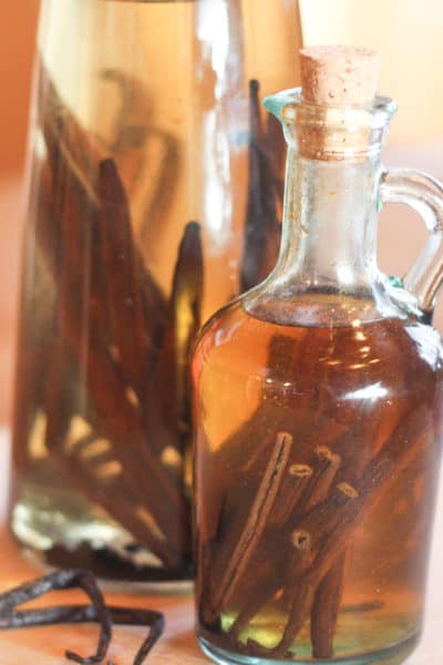Two glass bottles with vanilla beans for vanilla extract in them