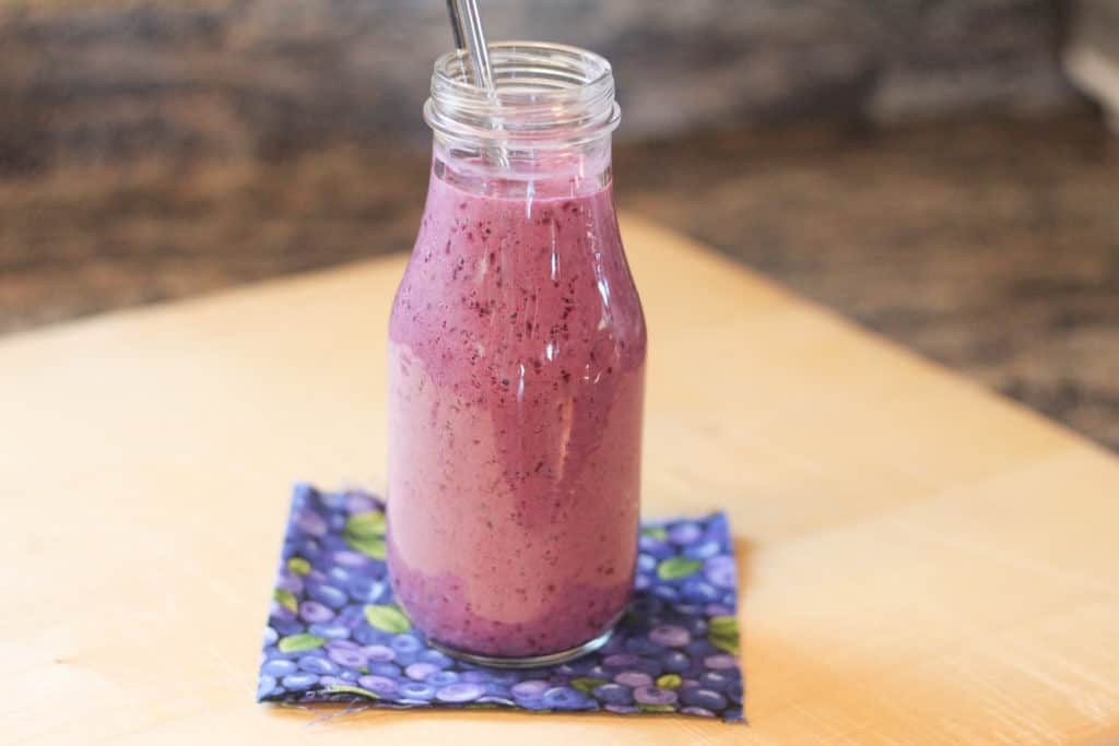 Small glass bottle filled with blueberry smoothie
