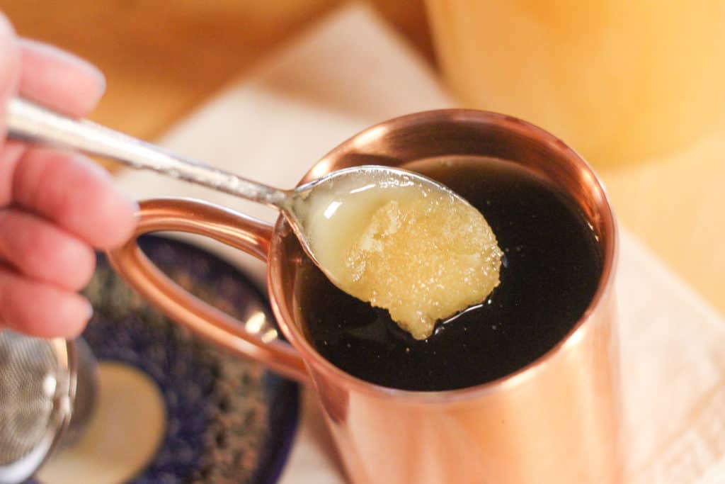 Spoonful of crystallized honey stirred into a cup of tea.