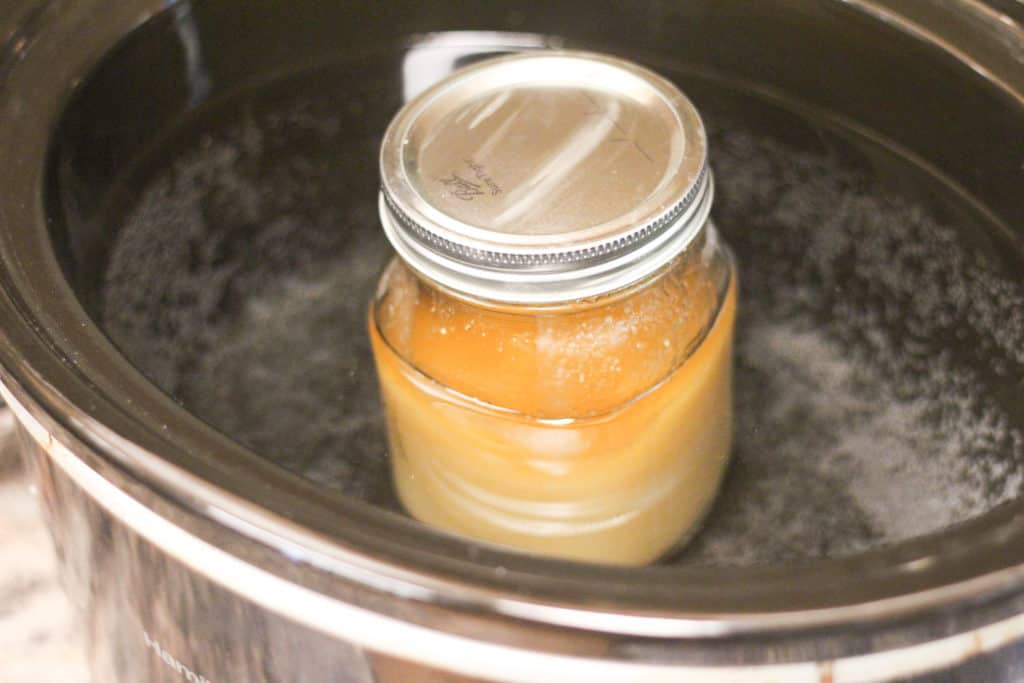 Jar of crystallized honey in a crock pot full of water.