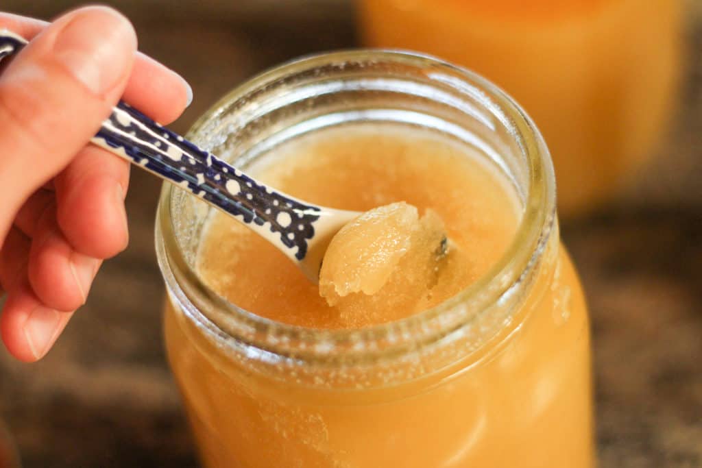 Spoonful of crystallized honey in a jar.