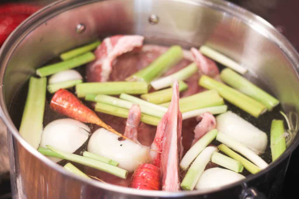 A stock pot full of water and broth ingredients 