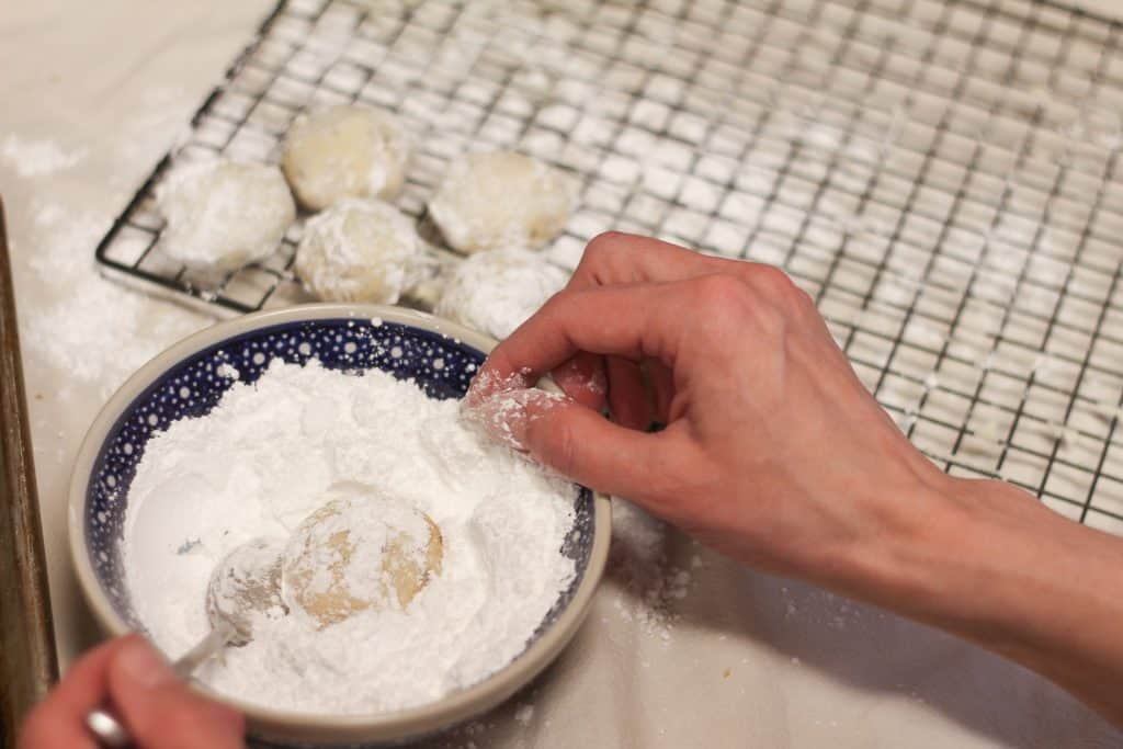 Cookies being rolled in powdered sugar