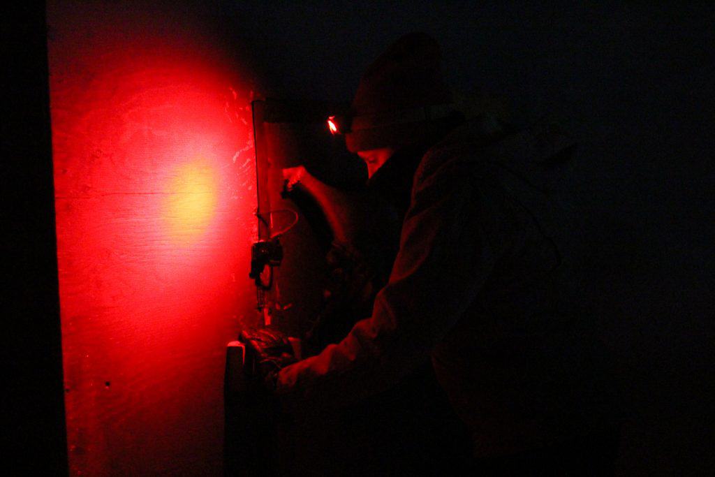 Beekeeper entering shed at night with red lamp