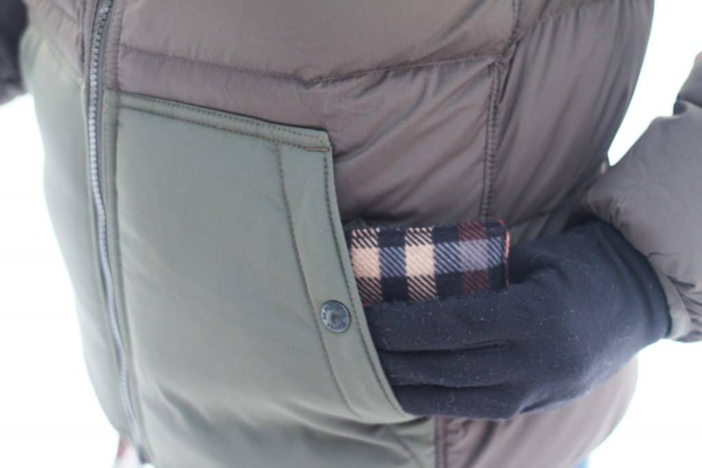 A gloved hand putting a diy reusable hand warmer into a coat pocket