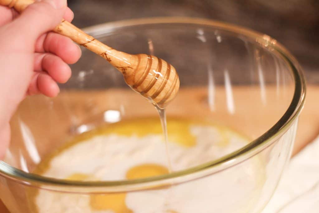 honey being drizzled into a bowl with batter