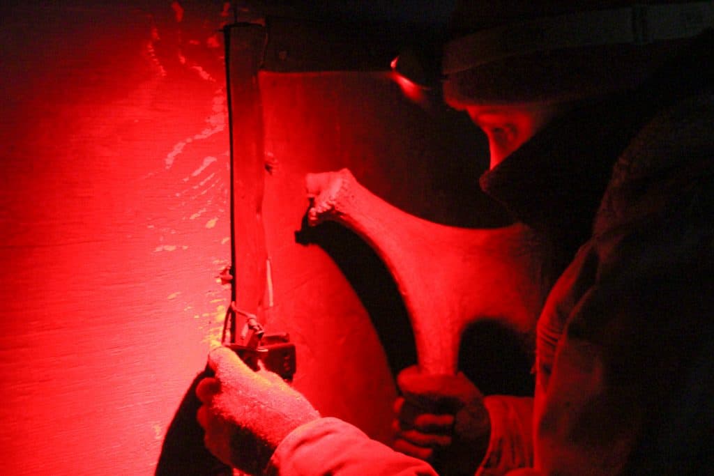 nighttime with red light, beekeeper entering small building