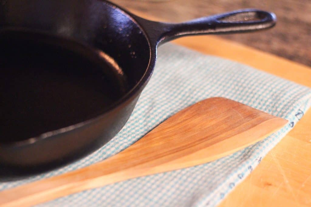 A cast iron skillet with a wooden spatula