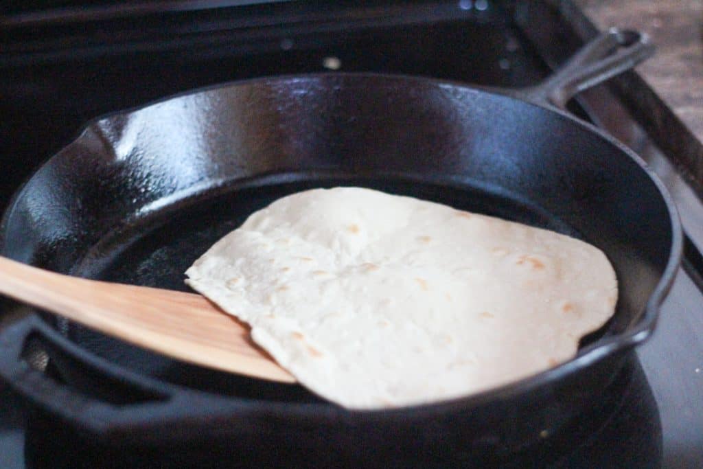 Tortilla being cooked in a cast iron skillet