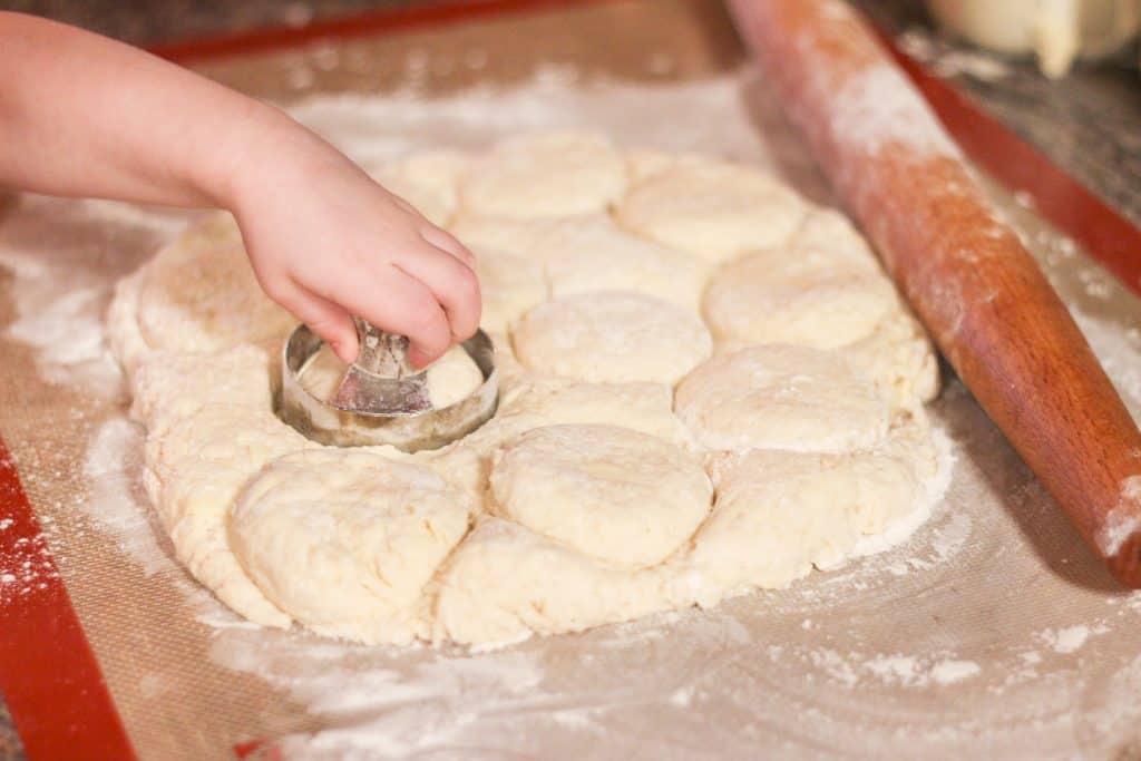 A child's hand cutting out biscuits