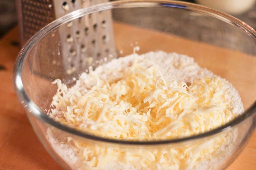 A glass bowl full of flour and shredded butter