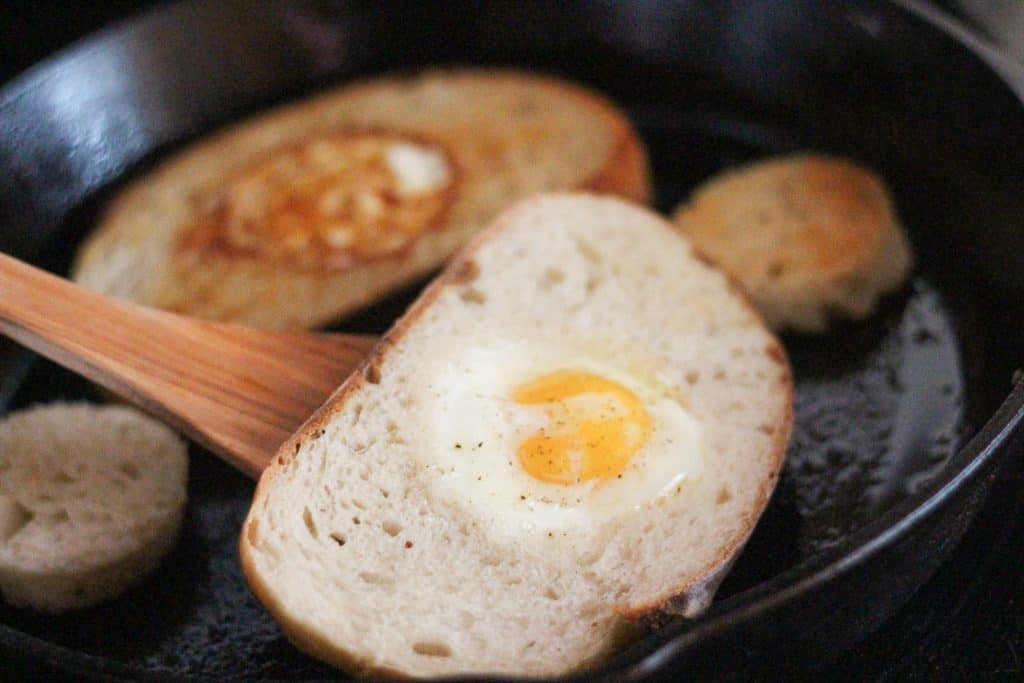 A spatula flipping the bread and eggs
