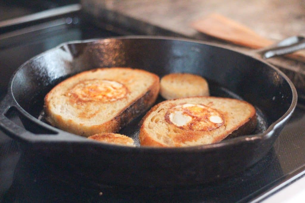 Eggs in the center of toast cooking in a skillet