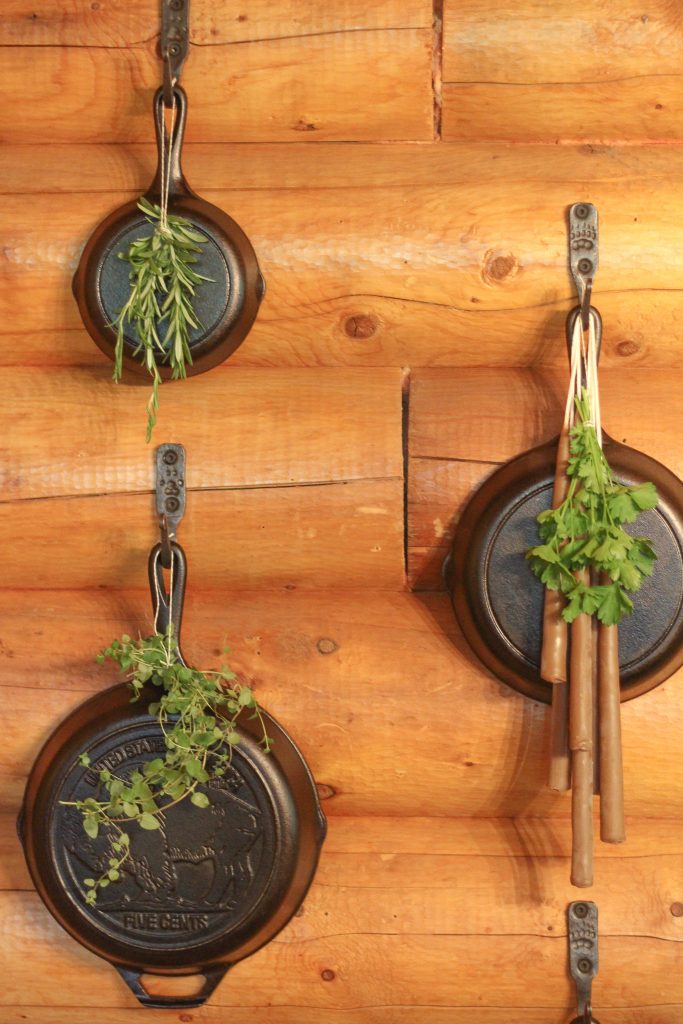Hooks holding cast iron skillets and drying herbs hanging on them