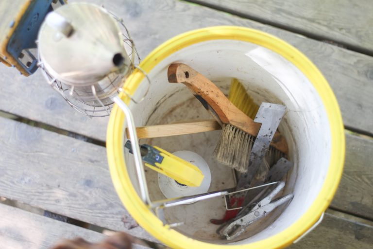 Looking down into a 5-gallon bucket full of beekeeping tools