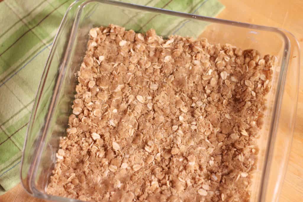 A glass dish with an oatmeal crust spread on the bottom