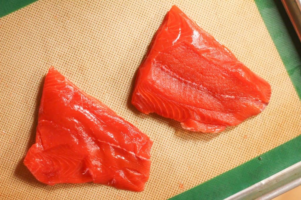 2 raw salmon fillets on a sheet pan