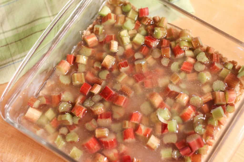 A glass dish with chopped rhubarb drizzled with honey