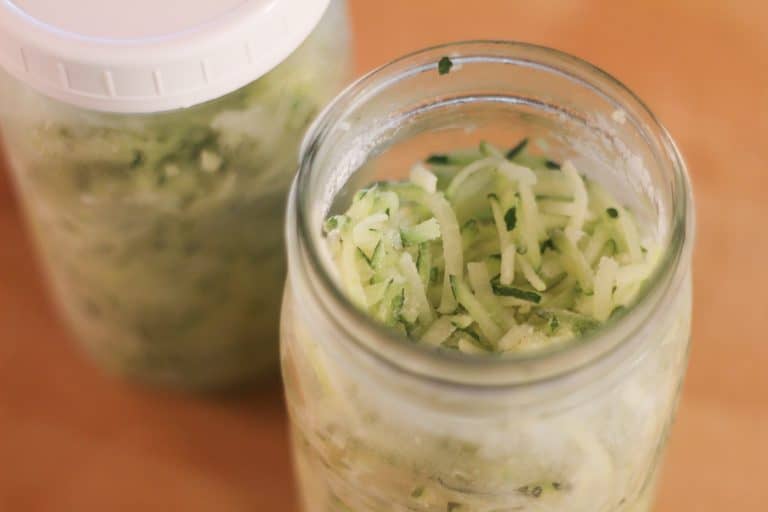 A glass jar of shredded, frozen zucchini
