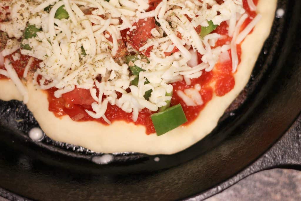 Raw pizza in a cast iron skillet before being baked