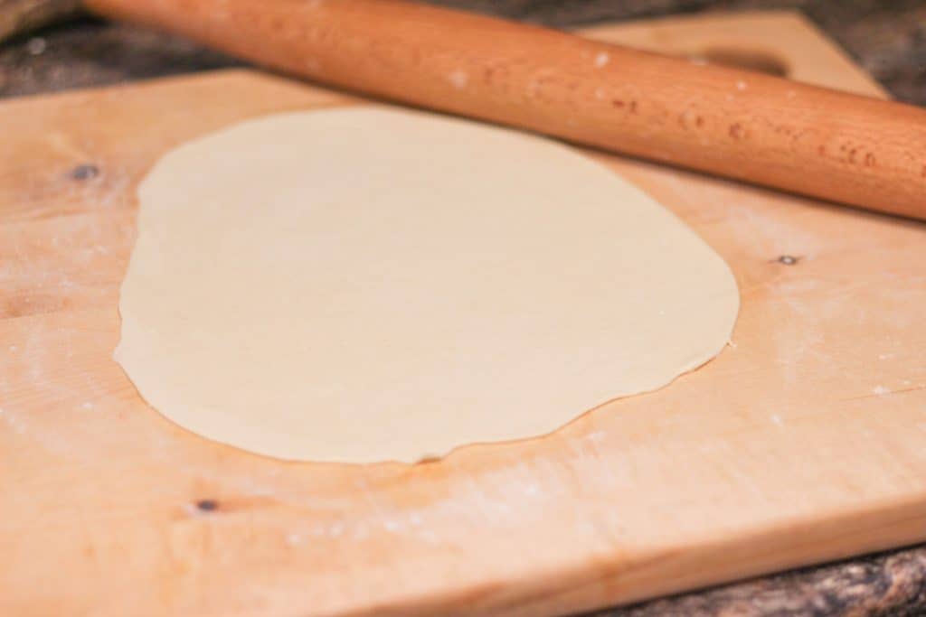 Sourdough pizza dough being rolled out with a rolling pin