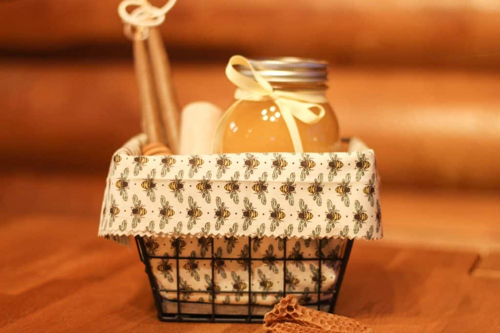 A honey gift basket with a jar of honey and two candles in it