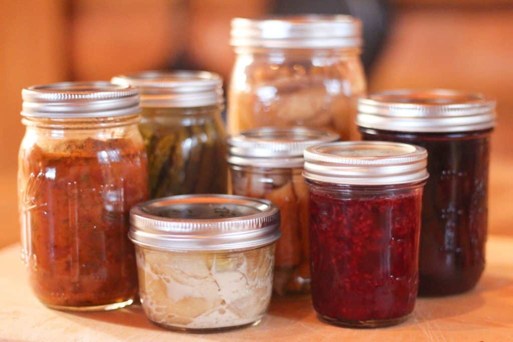 Several glass jars full of food showing sizes of canning jars