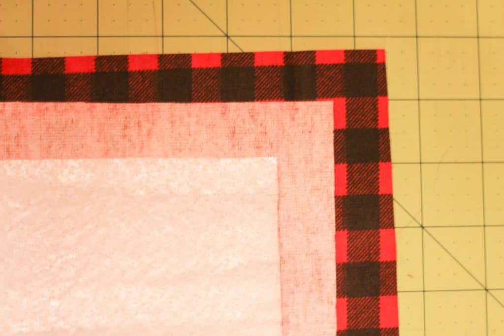 A square of right-side fabric, a square of inside-out fabric, and a square of insulbrite stacked to make a diy pot holder