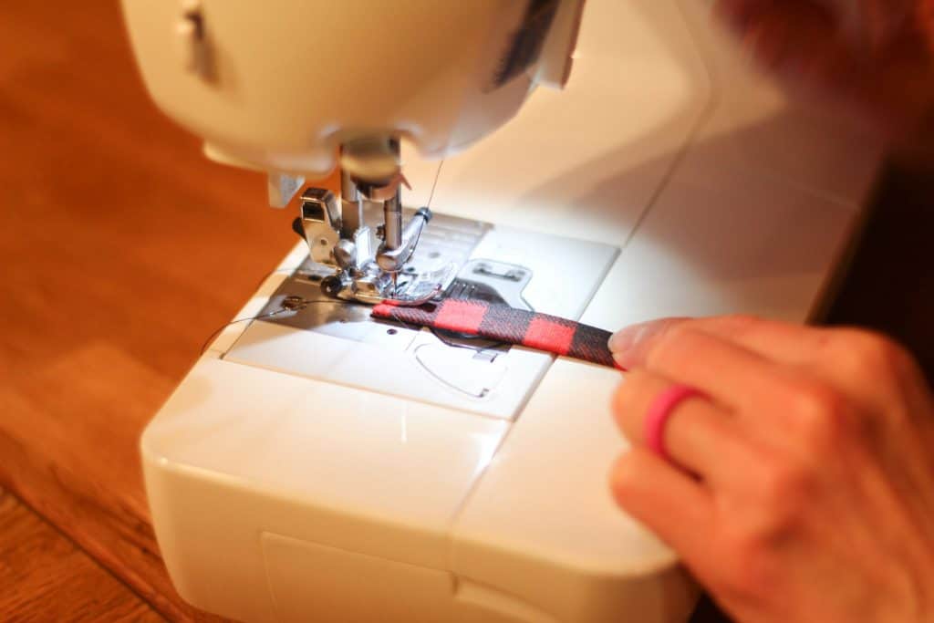 A sewing machine sewing down a strip of fabric to make a handle
