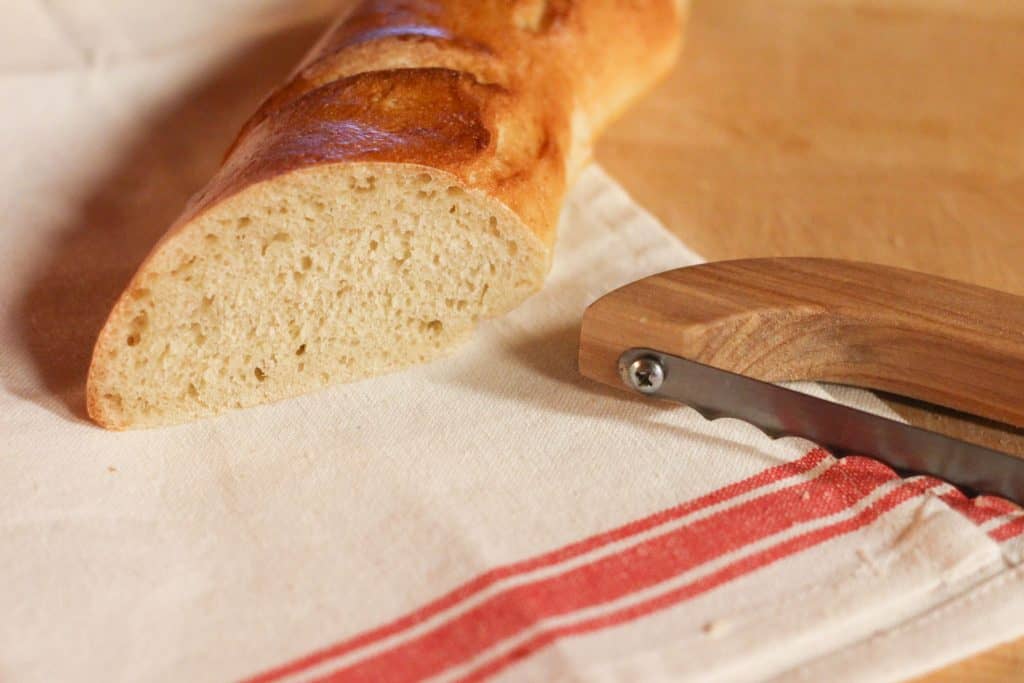 A cut piece of French bread and a knife