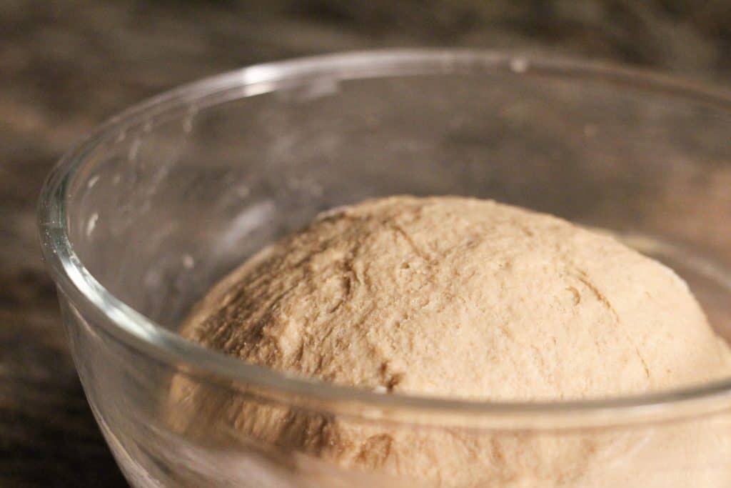 A ball of bread dough in a glass mixing bowl