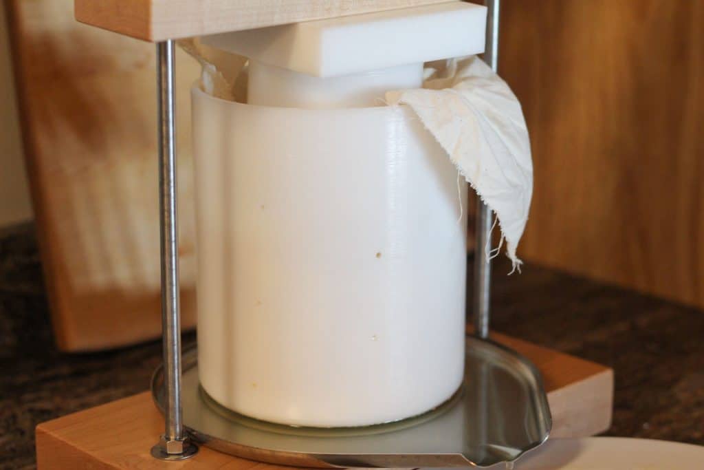 A cheese mold in a cheese press