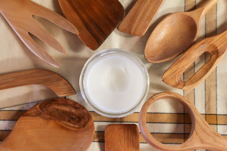 Wooden utensils laying in a circle with a jar of homemade spoon butter in the middle