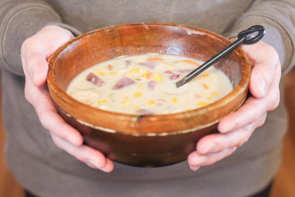 Hands holding a bowl of halibut chowder