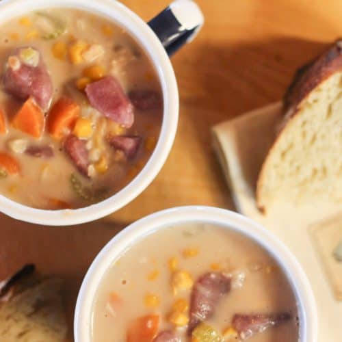 Two mugs full of halibut chowder with two slices of bread
