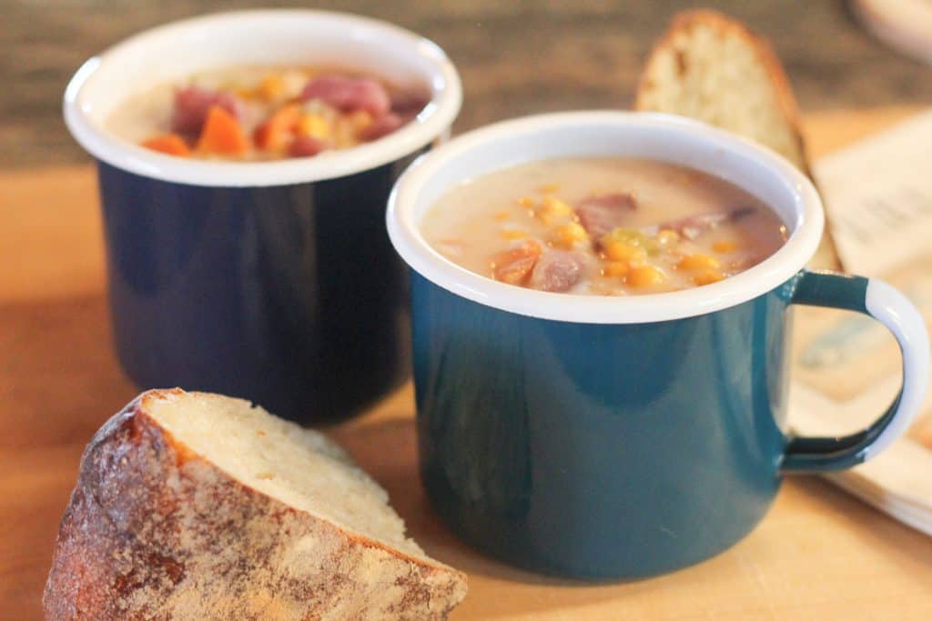 Two mugs full of halibut chowder with a piece of bread