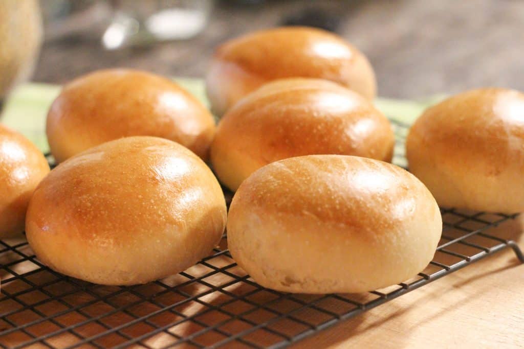 Freshly baked hamburger buns cooling on a wire rack