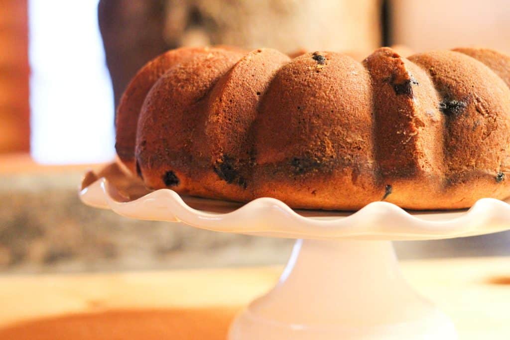A side of a whole blueberry bundt cake sitting on a cake stand.