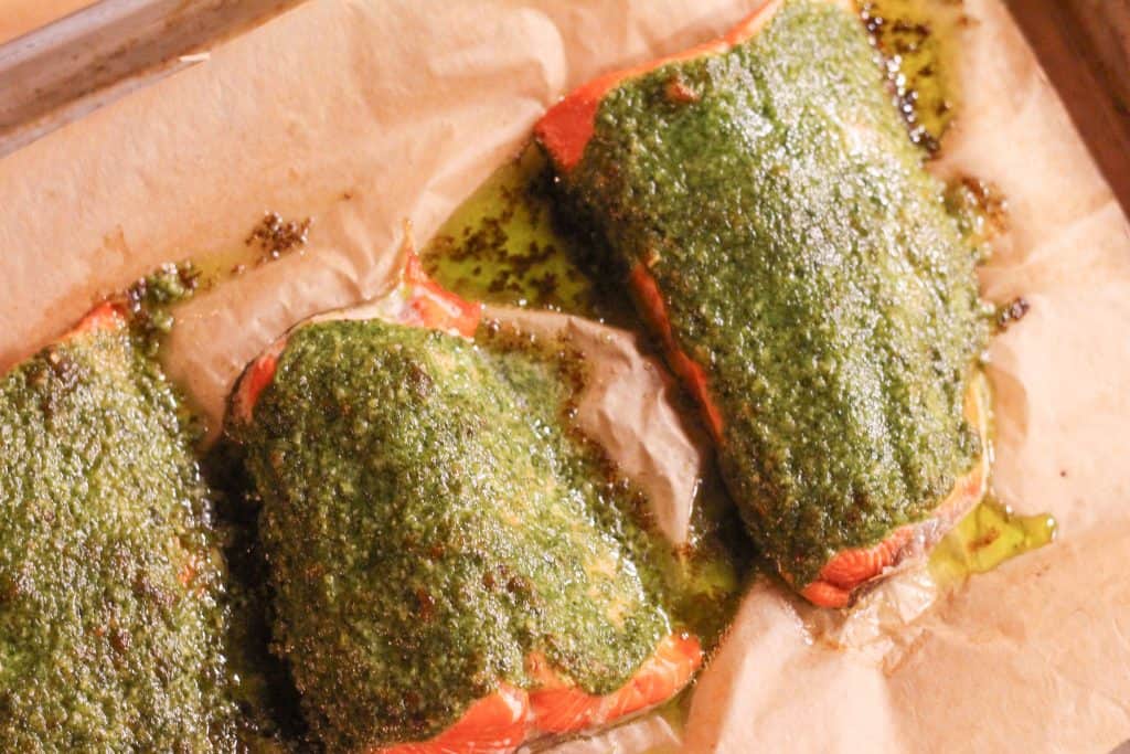 Cooked pesto salmon fillets on a baking dish