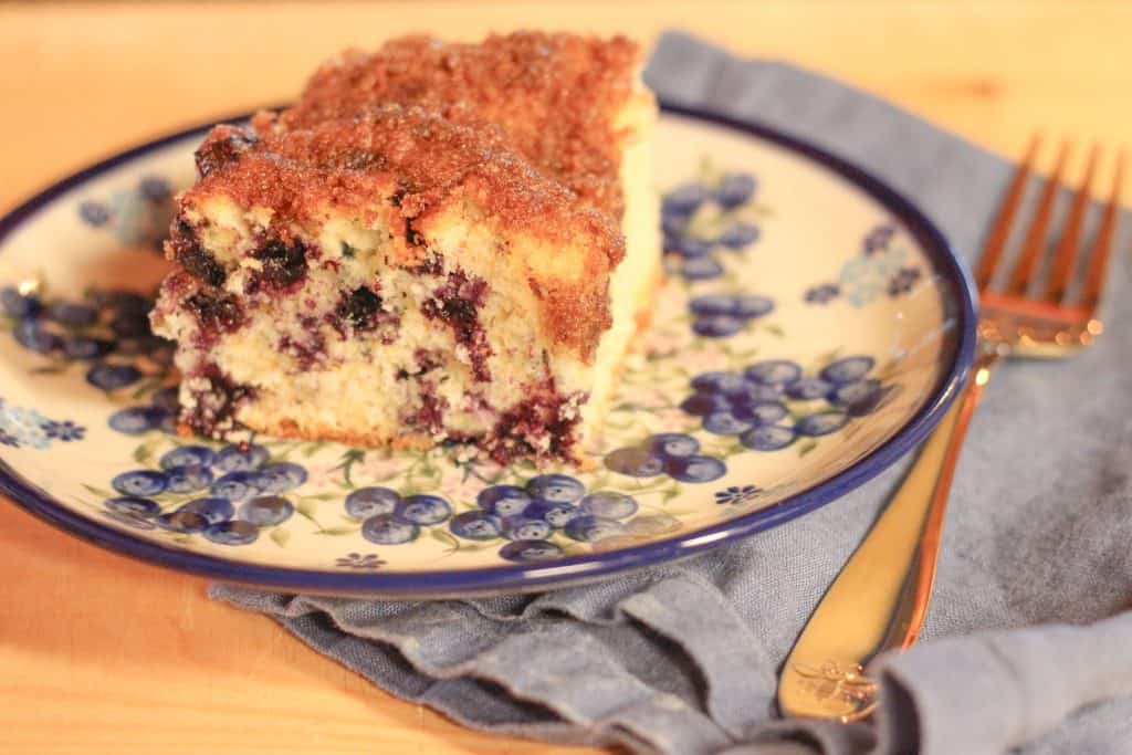 A piece of blueberry coffee cake on a plate with a fork